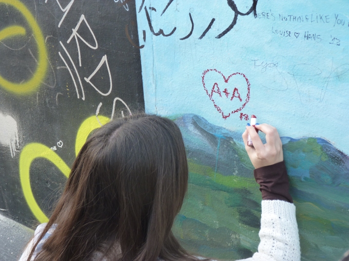 Chica pintando corazones en el cielo del muro (Berlín, 2014)